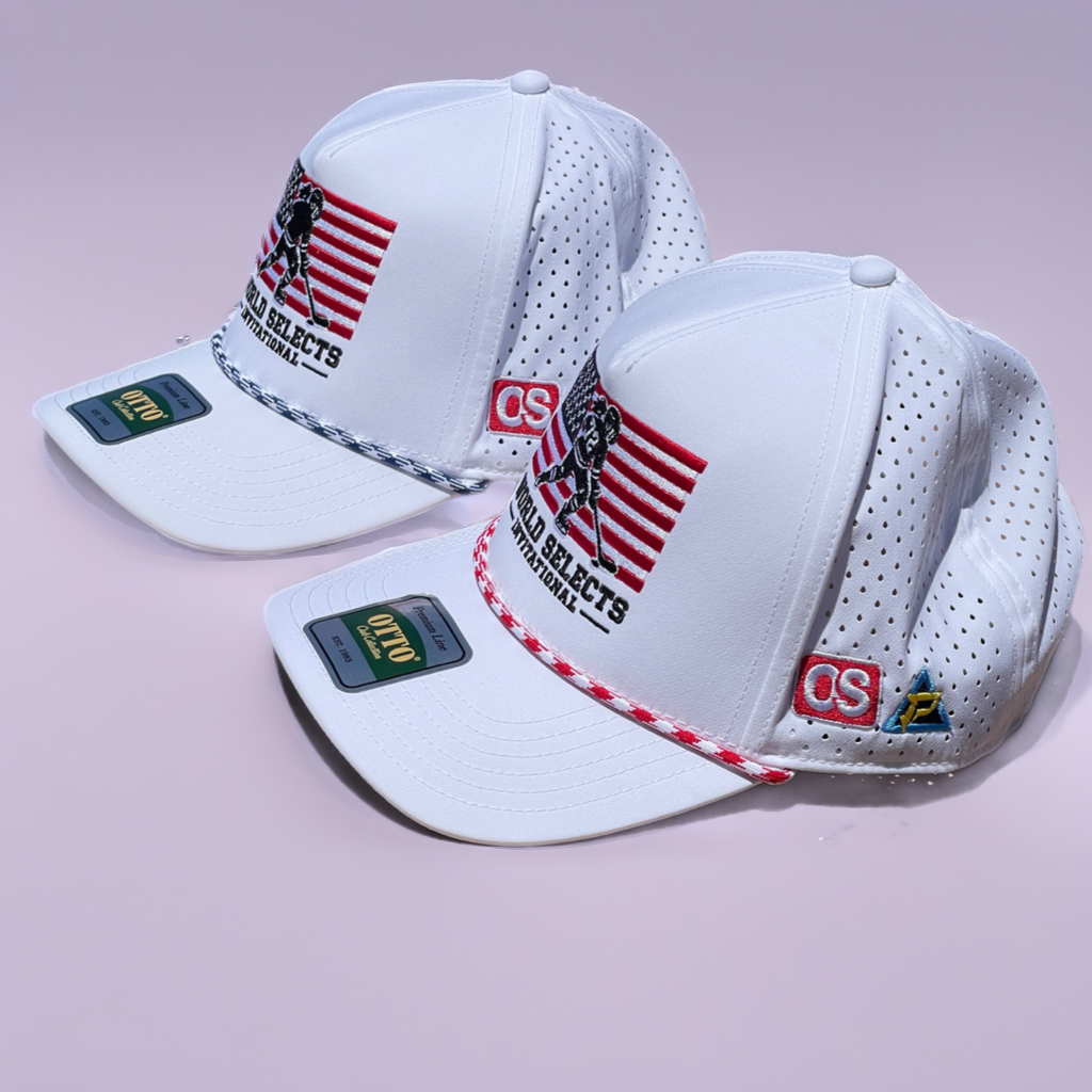 Two white CS:GO Selects basketball caps with red and black embroidered graphics, displayed on a light pink background.